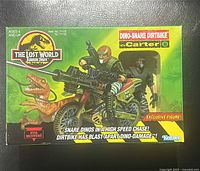 Front view of original boxed packaging showing toy dirtbike with mounted weapon, velociraptor figure, and exclusive Carter B figure.