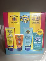 Front of the colorful box showing the three Banana Boat sunscreen tubes and a bonus packet of Wet Ones wipes with product branding and bilingual text.