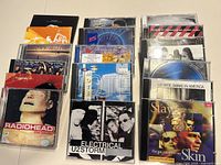Top view of front and back rows of various music CDs featuring artists like U2, Radiohead, Pearl Jam, and others, showing album artwork and jewel cases.