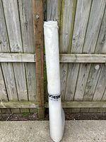 Full view of rolled Duchesne vapor barrier plastic standing upright against a wooden fence, showing branding on label.