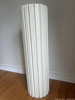 Full view of tall cream wood fluted pedestal with vertical groove details.