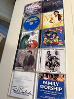 Photo showing front covers of 10 Christian music audio CDs arranged in three rows, including WOW Hits 2012, Newsboys live concert, Worship Box Hymns CD, Nicole C Mullen collection, two VeggieTales music CDs, Sam Cooke & The Soul Stirrers, Paul Baloche worship album, Family Worship guided by Donald S. Whitney, and a mixed compilation.