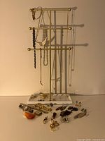 Full view of costume jewelry and wristwatches including necklaces on a jewelry stand and multiple pins and watches laid out on a tray.