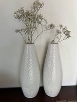 Pair of tall white contemporary vases with a hammered texture and dry foliage inserted in one.