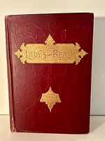 Front cover of The Lady's Realm Volume XXV 1908, showing embossed red cloth cover with gold stamped title and embellishments.