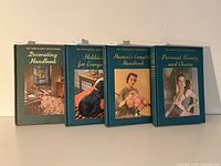 Four hardcover books in the set standing upright showing front covers with illustrated images and gold embossed titles