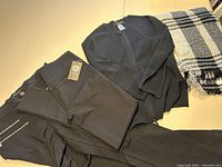 Black pants and cardigan laid flat with black and white scarf, showing overall lot contents