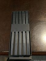 Top view of black chopsticks in black box, showing 10 pairs arranged in two rows with textured grip pattern near the top.