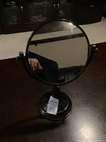 Front view of the 14-inch round makeup mirror on a dark pedestal base showing the reflective mirror surface and frame.
