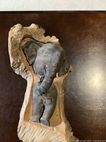 Front view of 20-inch elephant wall hanging sculpture showing elephant with one tusk missing mounted on natural wood backing.