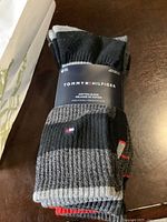 Four pairs of Tommy Hilfiger men's socks bundled together, showing label with brand and cotton blend fabric detail.
