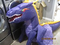 Full side view of the inflated dragon costume showing head, wings, and tail details.