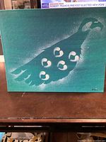 Full view of the painting showing the peacock against a green background with white markings and speckles, signed by Brad Castel.