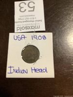 Front view of the 1908 USA Indian Head coin inside a white cardboard holder with handwritten label.