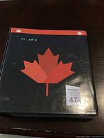Photo of the black binder with a red maple leaf on the cover labeled with lot number