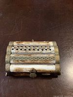 Closed view of the rectangular bone type jewelry box showing detailed engravings and metal accents on the exterior with metal clasp.