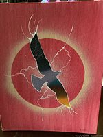 Full view of the painting showing stylized eagle flying against circular red sun with white lightning-like accents on textured canvas.