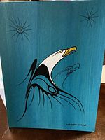 Front view of the Indigenous art painting showing a stylized white eagle on blue background, signed by artist.