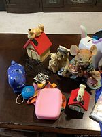 Photo showing children's figurines, piggy banks, and toys arranged on a table.