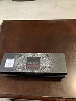 Closed CROC Infrared flat hair iron box with decorative silver pattern on black background and lot sticker.