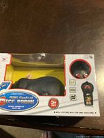 Front view of packaged remote control mouse prank toy in original yellow and white box with display window.