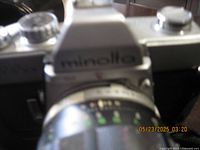 Close-up photo of the Minolta SRT 101 camera showing the brand name on the prism and part of the lens.