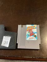 NES game cartridge with clear and colorful Super Mario Bros 2 label on front, laid flat on a brown surface.