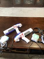 NSI Laser X set showing two laser guns and two wearable sensors on a dark wooden table.