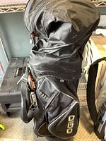 Oblique side view showing the bag's large compartments, zippered pocket labeled 'OGIO', and shoulder strap.