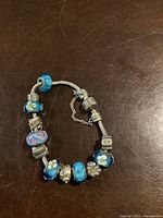 Full bracelet showing arrangement of various glass and silver charms on the silver snake chain.