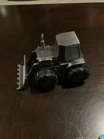 Left side view of pewter bulldozer coin box showcasing robust blade, tire and cabin details