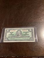 Front view of the 1937 Bank of Canada one dollar bill showing King George VI portrait and serial number 6141887 with signature error.