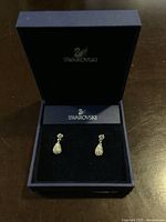 Swarovski drop earrings in blue box with black velvet interior, showing front with earrings inside.