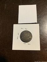 Obverse side of the commemorative coin showing 'CKAC 25 1922-1947' inscription, centered in a white cardboard holder.