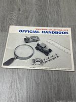 Front cover of the Matchbox Collectors Club Official Handbook showing vintage Matchbox model cars and a magnifying glass.