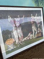 Full view of the framed artwork showing football players celebrating with trophy and bowl of oranges