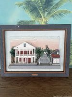 Front view of 3D wooden art piece showing detailed Key West buildings scene and palm tree background.