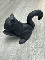Front profile of the cast iron squirrel shaped nutcracker showing the full body and curled tail on a wooden surface.