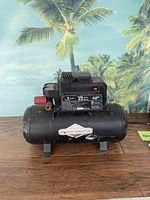 Full view of the Briggs & Stratton 3 gallon oil-free air compressor showing the main tank and compressor unit with visible branding and wear.