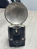 Front view of Brownie Flash Six-20 camera with open metal flash reflector showing single lens and controls.
