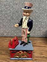 Front view of the cast iron Uncle Sam coin bank showing red purse, patriotic colors, and detailed sculpture.