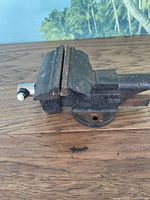 Side view of the Craftsman table vice showing the clamping jaws and mounting base on a wooden surface with signs of rust.