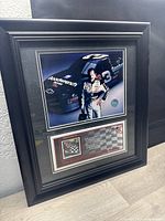 Angled full view of the framed item showing the Dale Earnhardt picture, stamp and text mat.