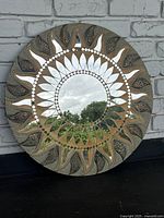 Front view of decorative sun mirror showing central mirror and sun ray design with intricate patterning.