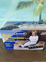 Box showing Dr. Scholl's Body X-Pressions cushioned massage mat with image of woman using the mat and description of product features