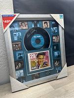 Full view of the framed collectible wall art showing the record, postage stamp, and photo border.