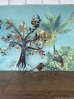 Metal tree wall art with fall leaves and two birds on wooden surface, tropical wall background