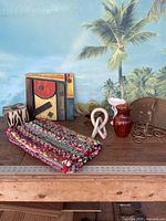 Overview of various household decorative items arranged on a wooden surface against palm tree wall art background depicting the lot contents.
