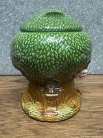 Front view of green leafy tree-shaped cookie jar with Keebler elf decoration on bark base and Keebler tag attached