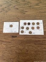 Lot of Lincoln pennies on white paper with handwritten dates and notes, showing circulated condition.